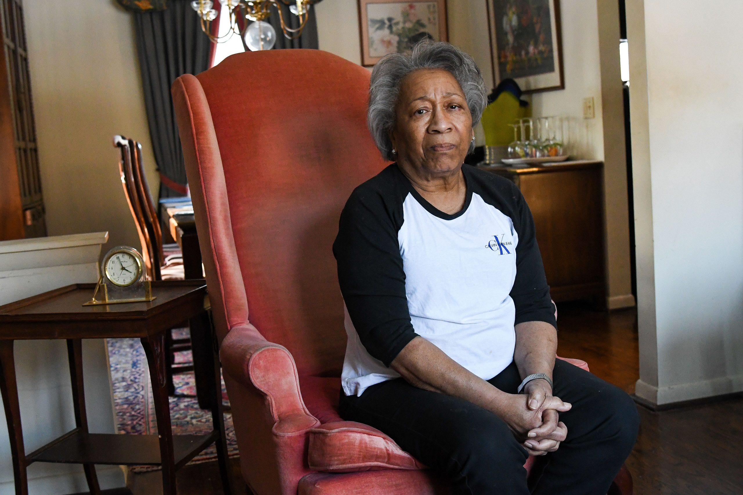 A woman sitting in a red armchair looks at the camera.