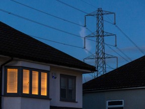 A light on at a residential home near an electricity transmission tower in Upminster, UK, on Monday, July 4, 2022. The UK is set to water down one of its key climate change policies as it battles soaring energy prices that have contributed to a cost-of-living crisis for millions of consumers. Photographer: Chris Ratcliffe/Bloomberg